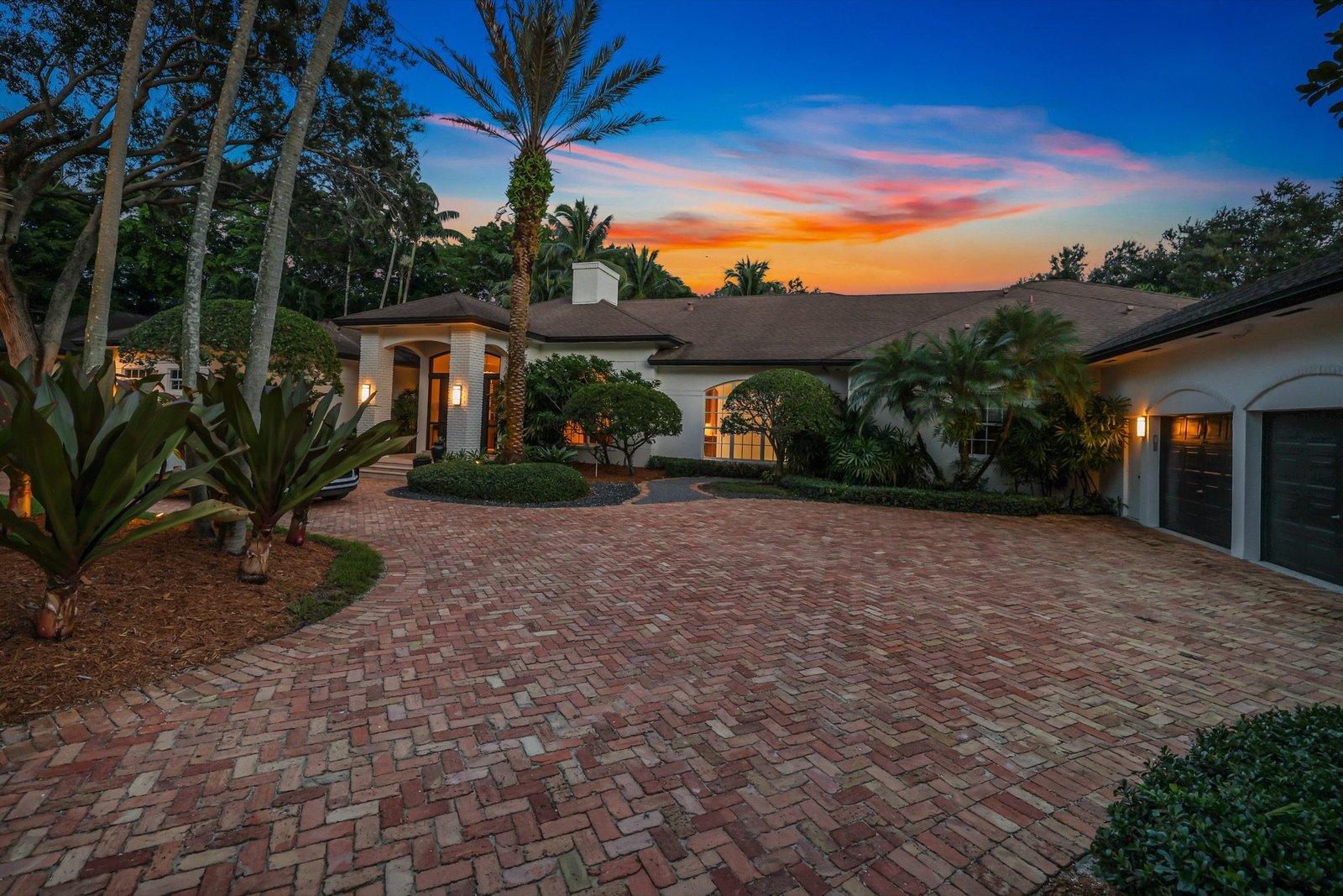 Circular brick driveway and three-car garage at twilight