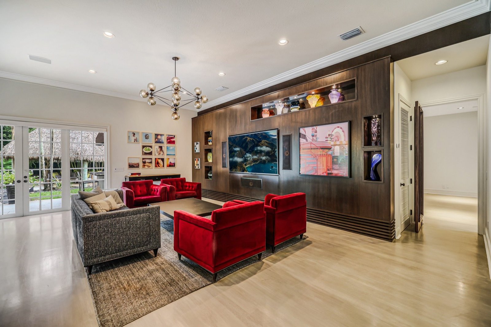 Family room with a dark wood media wall and french doors onto the pool terrace
