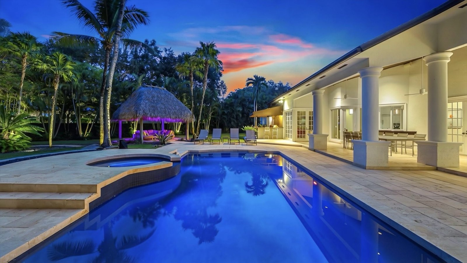 The heated saltwater pool at twilight, looking toward the tiki hut and covered terrace